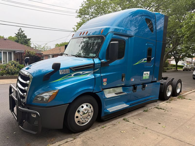 Blue Freightliner Cascadia sleeper semi tractor parked at a curb